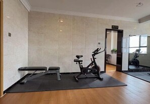 Uma academia com equipamentos de ginástica, um banco e um espelho grande na parede.