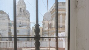 A view through a window with a metal grille, featuring a historic building with domed architecture and a bell tower. - Posadilla Apartment Cádiz (Cádiz)