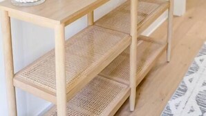 Ein Holzkonsolentisch mit einem Spiegel, einer weißen Lampe und zwei Glasbehältern mit Dekorationselementen.