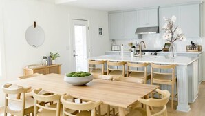 Eine moderne Küche mit hellblauen Schränken, einer zentralen Kochinsel und Holzkästen um einen Esstisch.