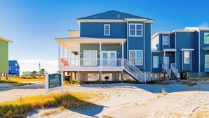 Et hus ved stranden med en overdækket veranda, en trappe og et skilt med Southern Vacation Rentals.