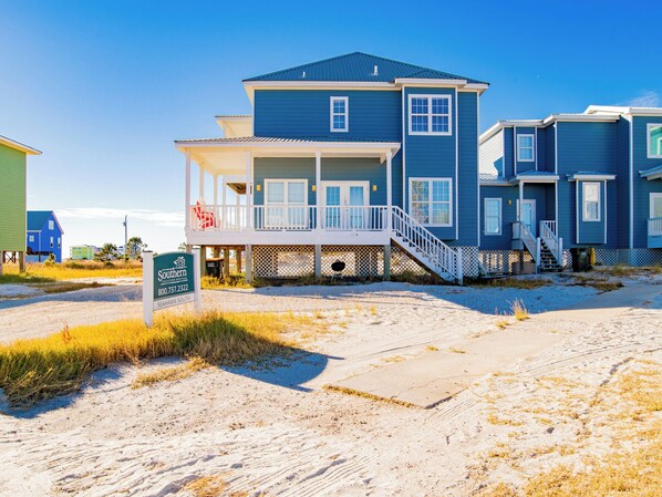 A beachfront house with a covered porch and a sign indicating Southern Vacation Rentals.