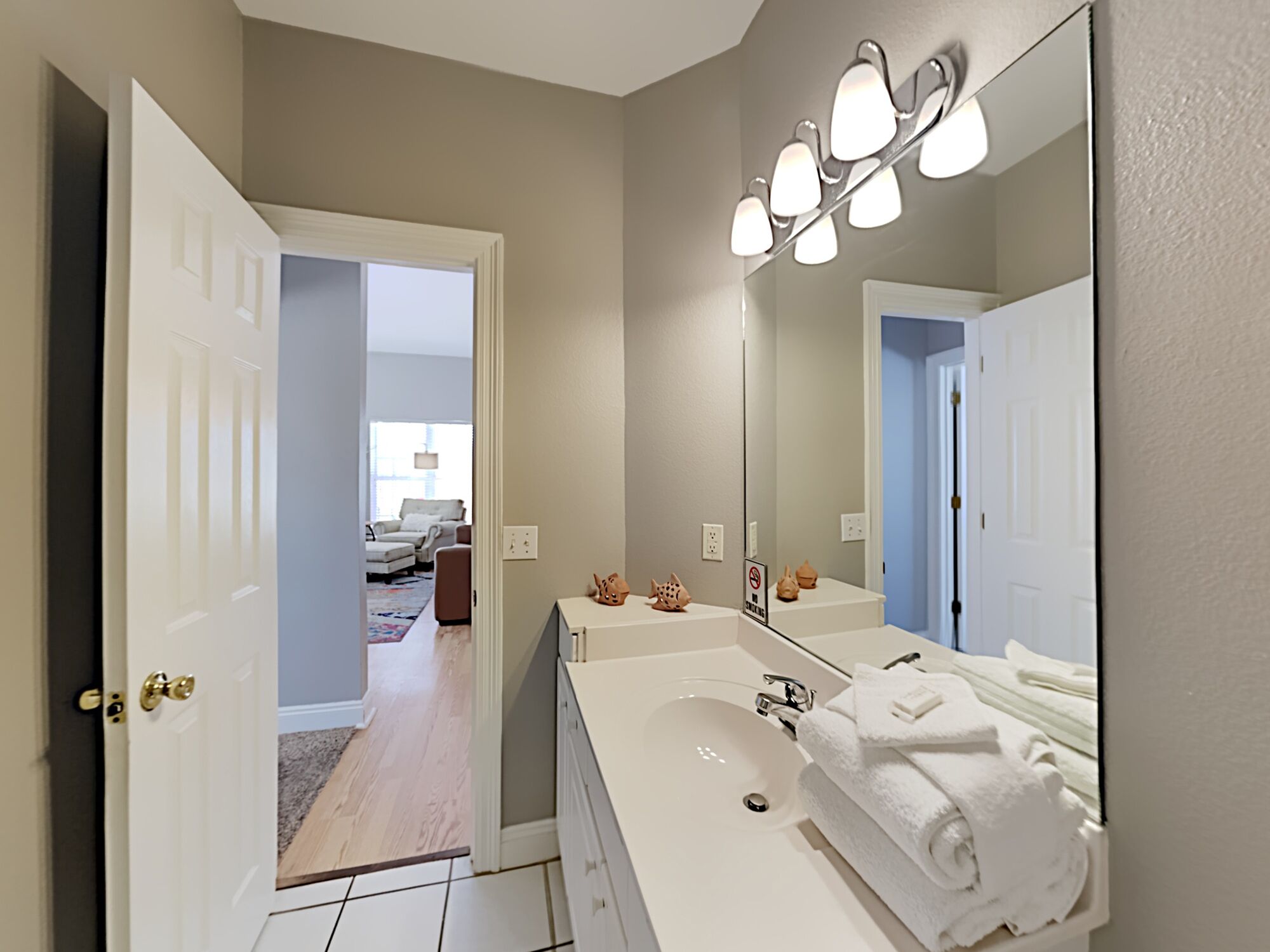 A bathroom with a white sink, a large mirror, and a towel rack.