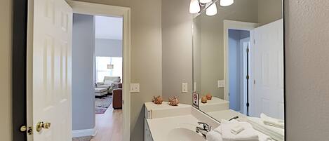 A bathroom with a white sink, a large mirror, and a towel rack.