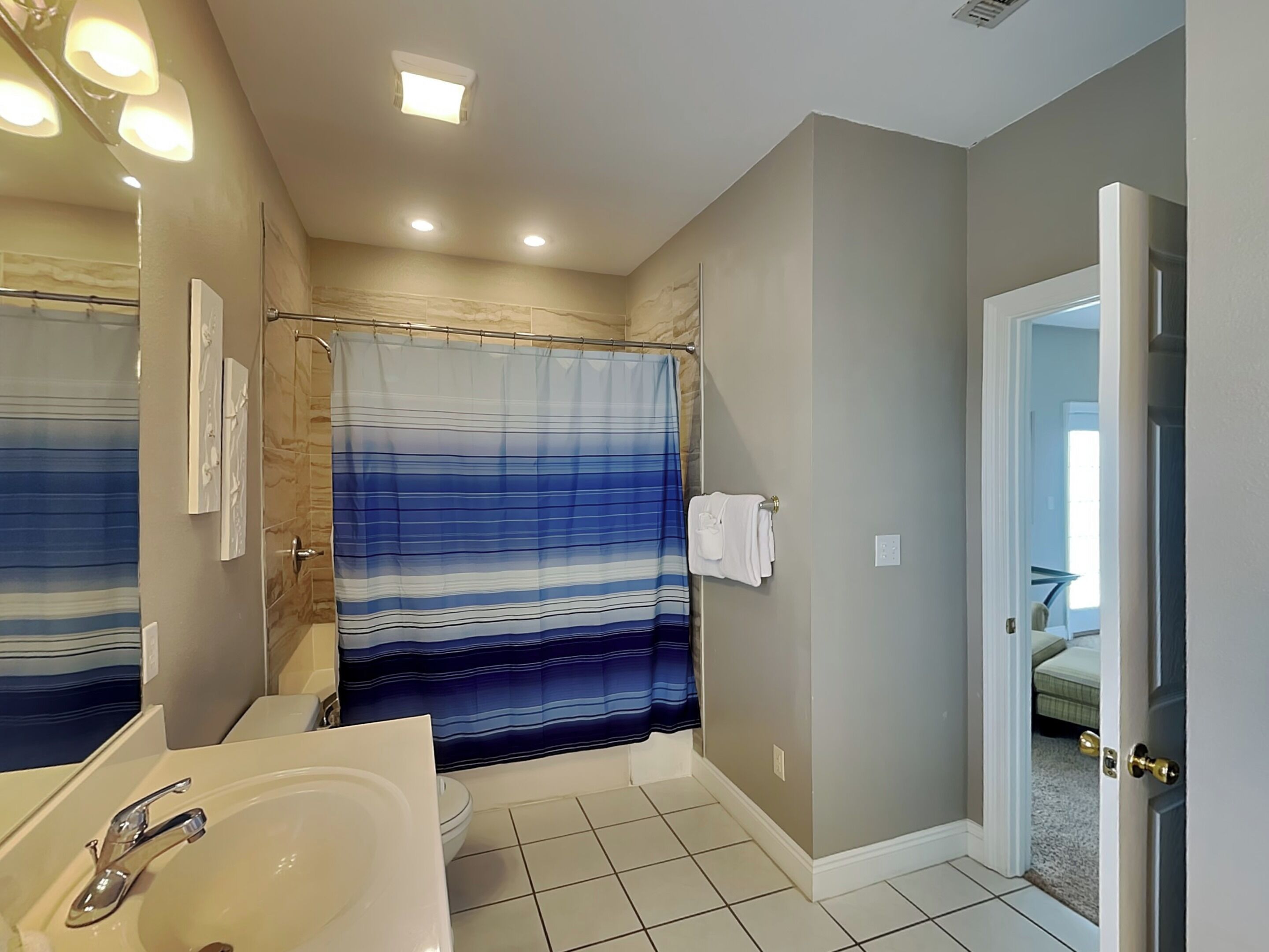 A bathroom with a striped shower curtain, a sink, and a toilet.