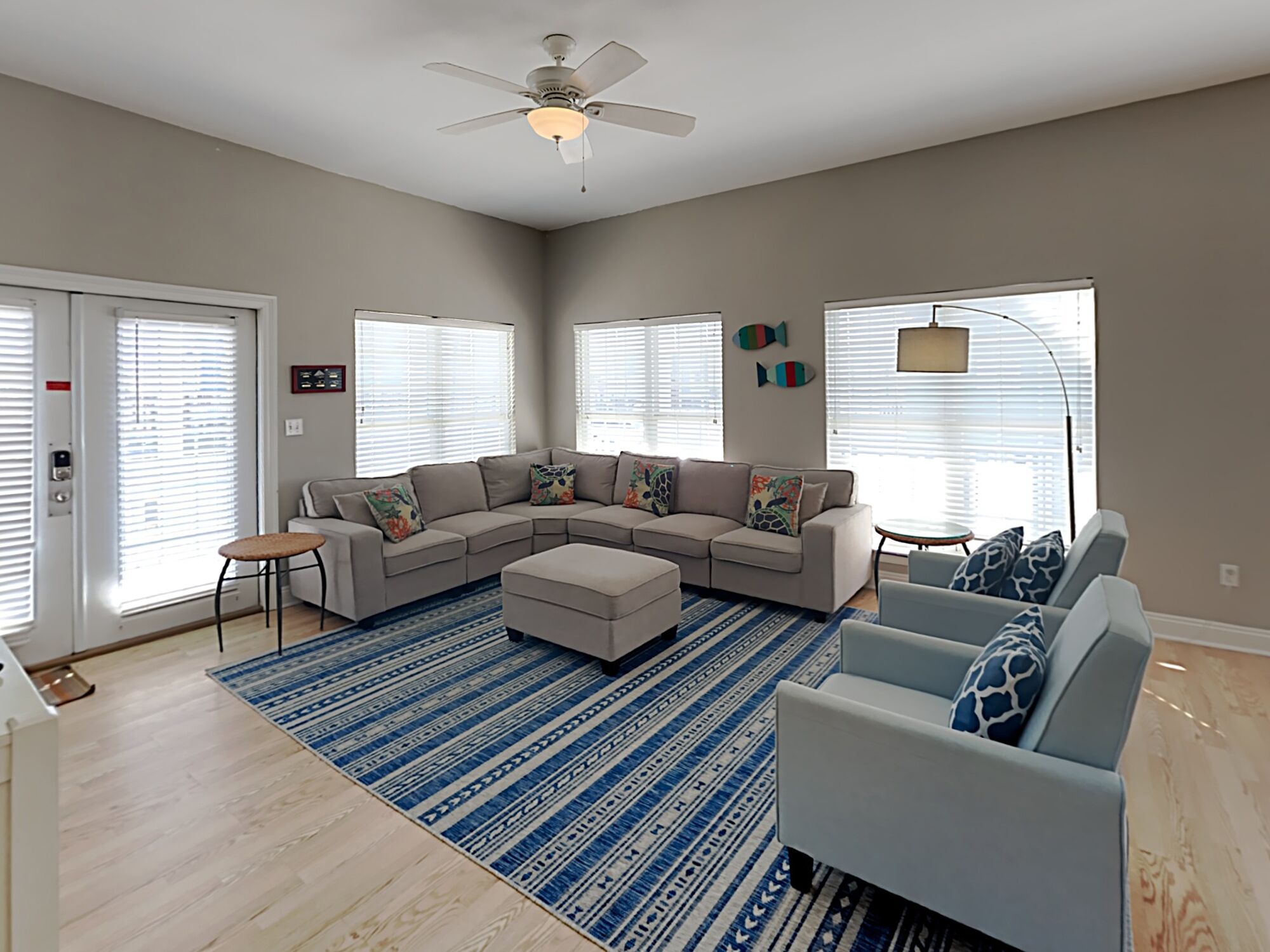 A spacious living room with a sectional sofa, a round coffee table, and a blue patterned rug.