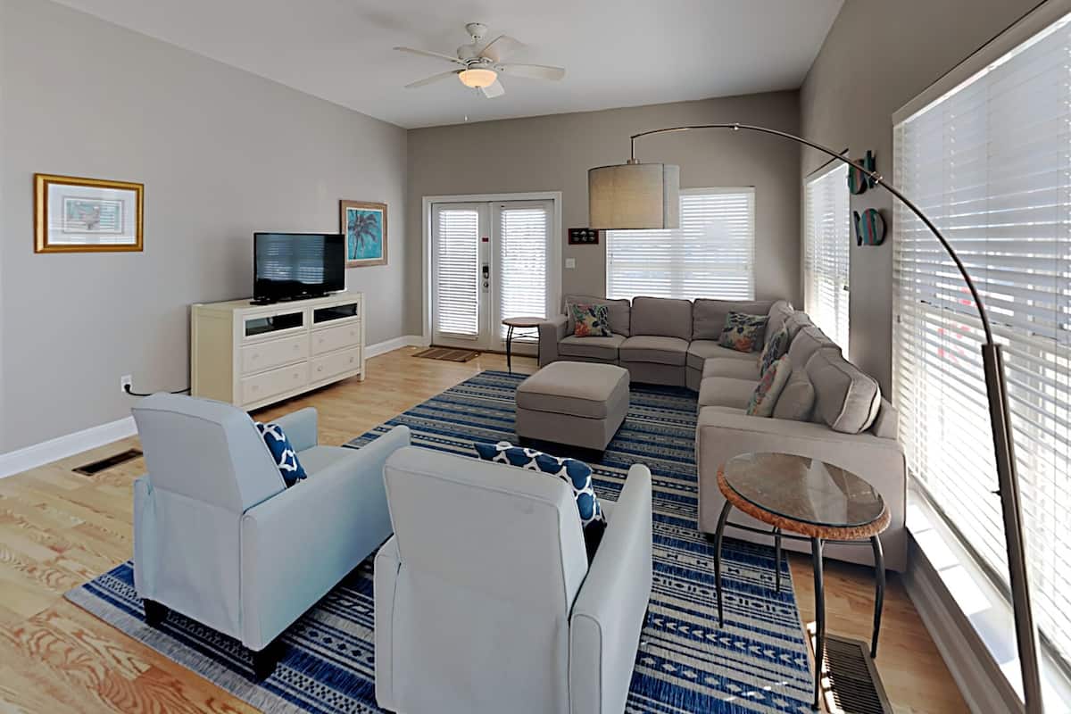 A modern living room with a sofa set, a television, and a ceiling fan.