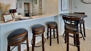Una cocina con barra, que incluye taburetes, lámparas colgantes y un reloj en la pared.