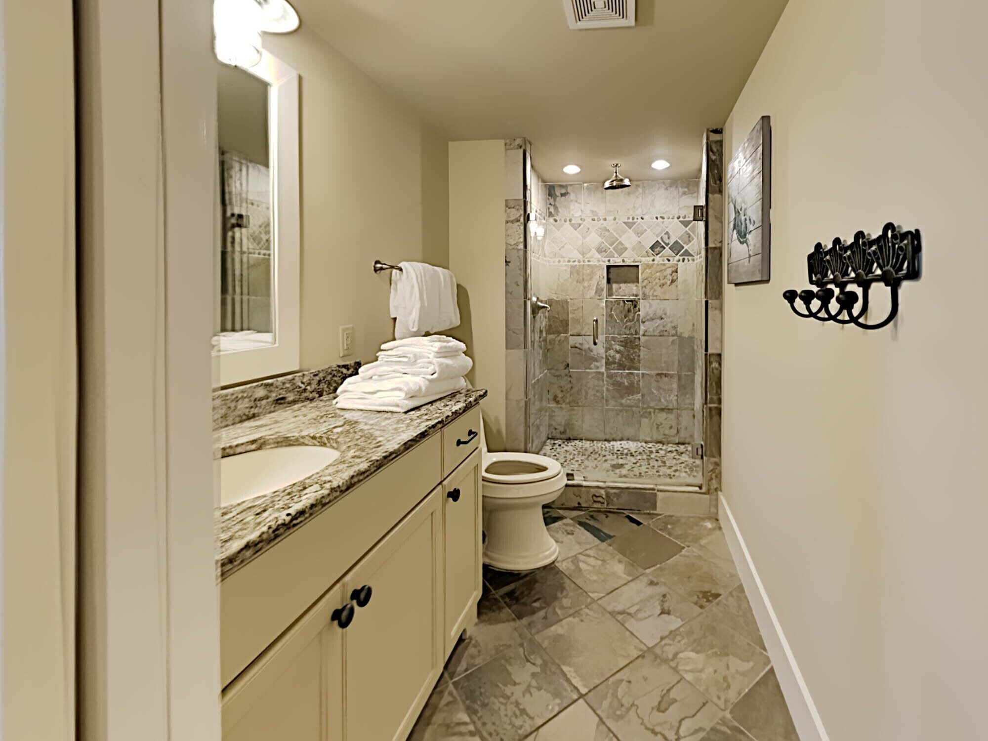 A modern bathroom with a marble countertop, a toilet, and a shower area.