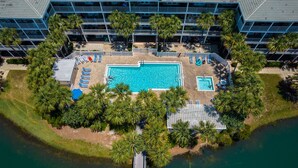 An aerial view of a hotel with a central swimming pool surrounded by palm trees and lounge chairs. - Gulf Place Six Palms #2B - BB's Hideaway by Southern Vacation Rentals (Santa Rosa Beach)