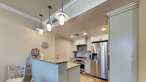 A modern kitchen with a central island, stainless steel appliances, and pendant lighting. - Gulf Place Six Palms #2B - BB's Hideaway by Southern Vacation Rentals (Santa Rosa Beach)