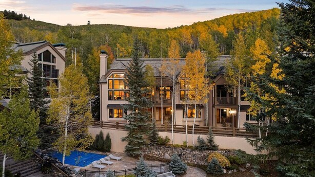A multi-story building with a pool, surrounded by trees and a hilly landscape. - 5 Beds in BC - Ski In, Hot Tub, Pool (Beaver Creek)
