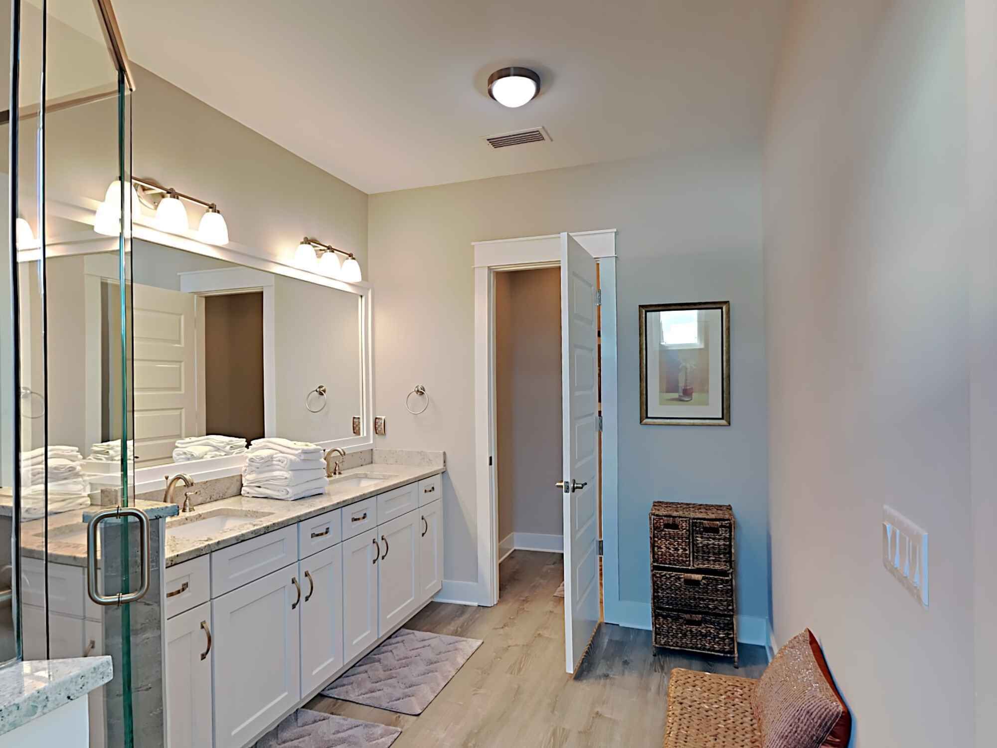 A modern bathroom with a double sink, large mirror, and a walk-in shower.