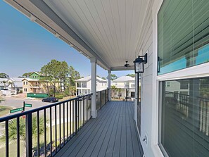A covered balcony with a view of the neighborhood, including houses and a street sign.