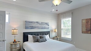 A bedroom with a large bed, two bedside tables with lamps, a ceiling fan, a window with blinds, and a wall-mounted artwork. - Sunshine Vacation Home by Southern Vacation Rentals (Miramar Beach)