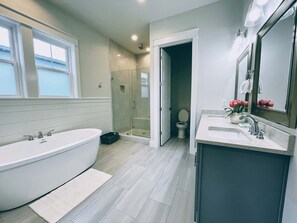 A modern bathroom with a freestanding bathtub, a shower enclosure, and a vanity with a mirror. - Seabreeze by Southern Vacation Rentals (Santa Rosa Beach)