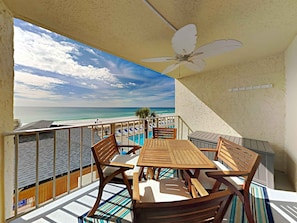 Enjoy the ocean view from this balcony with a table and chairs.