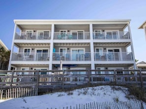 Stunning beachfront building with balconies on each floor, offering ocean views.