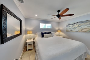 Relax in this serene bedroom with a large bed, bedside tables, and a ceiling fan.