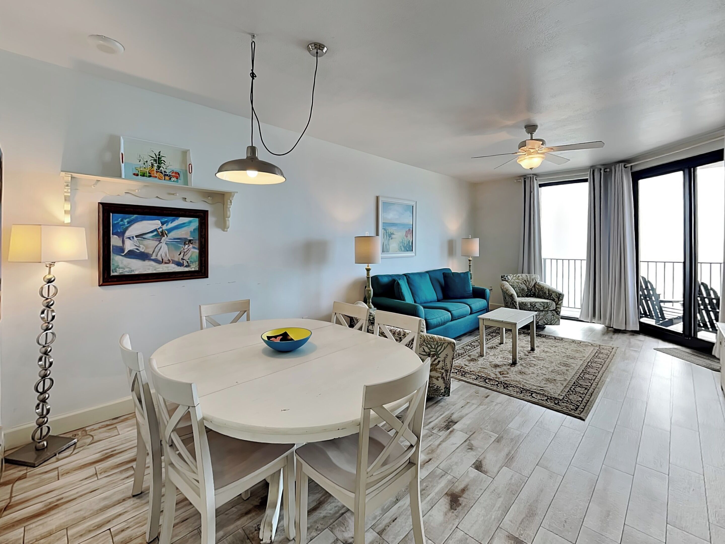 Un salon moderne avec une table à manger blanche, un canapé bleu et un ventilateur de plafond.