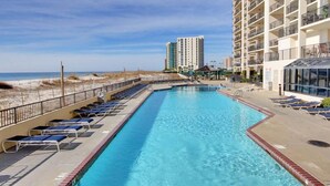 A swimming pool with lounge chairs, a beach view, and high-rise buildings in the background. - Phoenix X by Southern Vacation Rentals (Orange Beach)