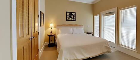A bedroom with a bed, a ceiling fan, a nightstand, and a window with blinds.
