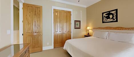 Un dormitorio con cama, armario de madera y ventilador de techo.