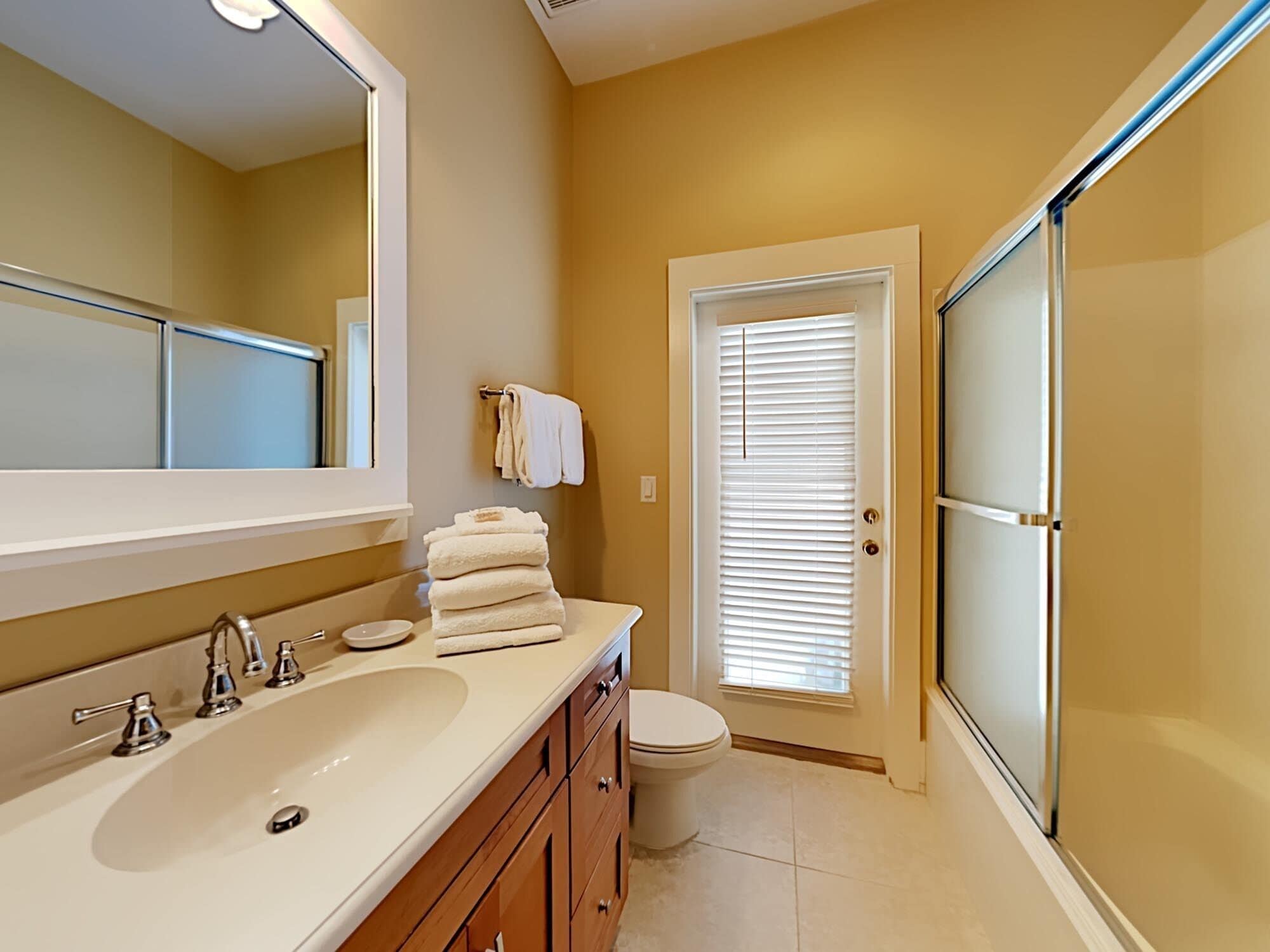 A bathroom with a large sink, mirror, and toilet.