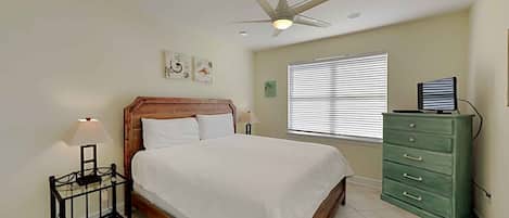 A bedroom with a bed, a nightstand, a dresser, a ceiling fan, and a window with blinds.