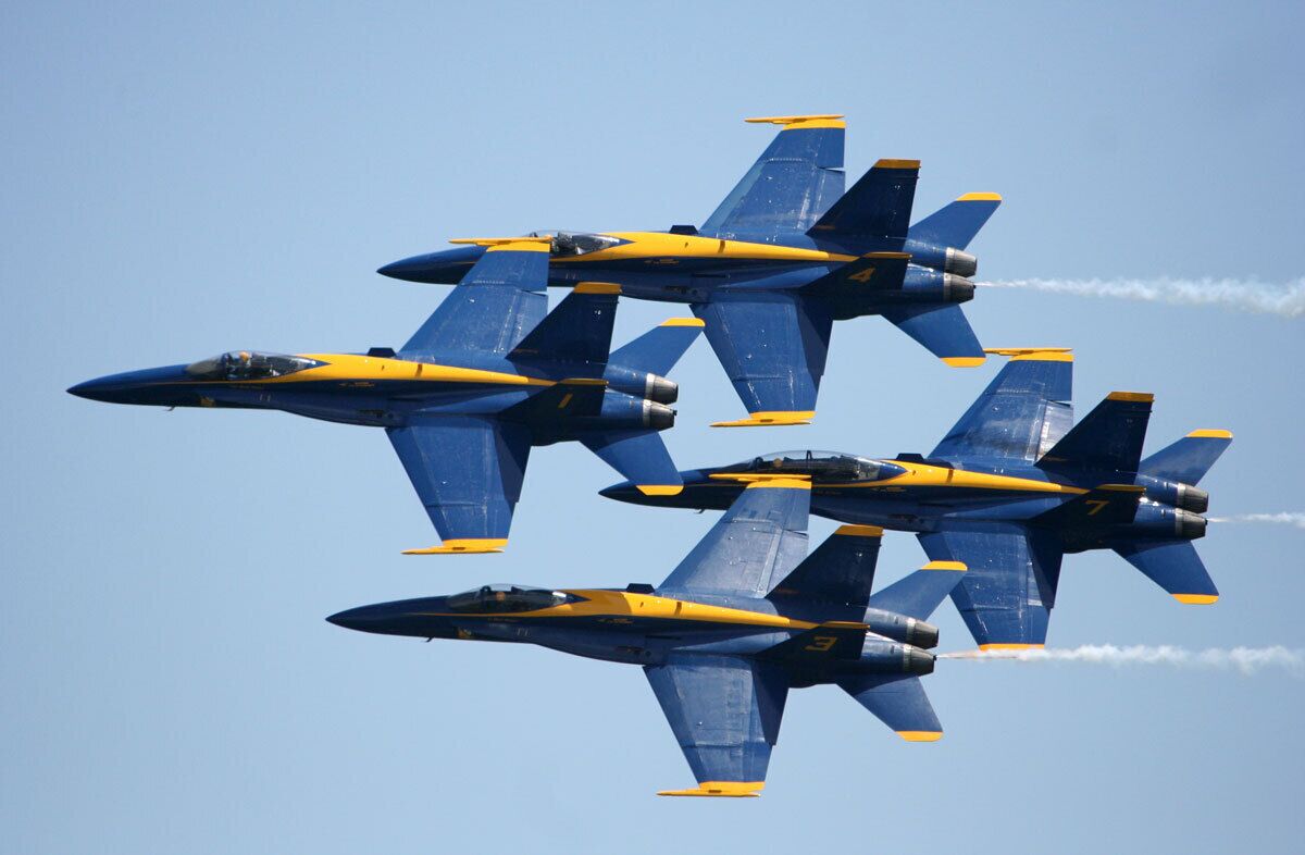 Vier blaue und gelbe Flugzeuge fliegen in Formation.