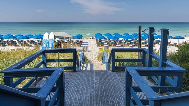 A beachside view with a wooden staircase leading to beach chairs and umbrellas. - Seychelles #301 by Resort Collection (Panama City Beach)