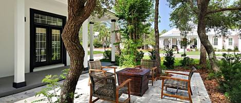 A patio with wicker furniture, a wooden table, and a pergola.