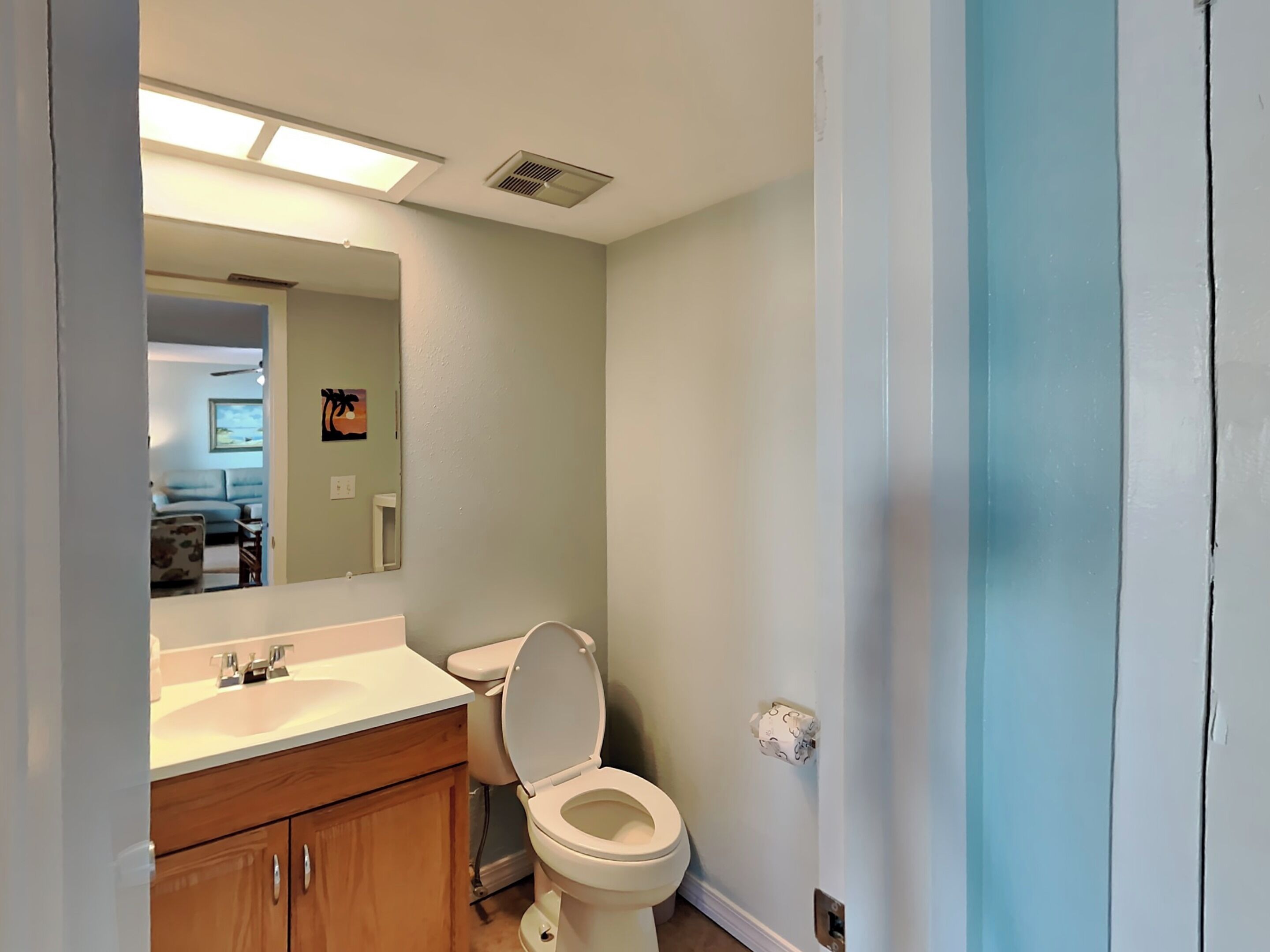 A bathroom with a toilet, sink, and mirror.