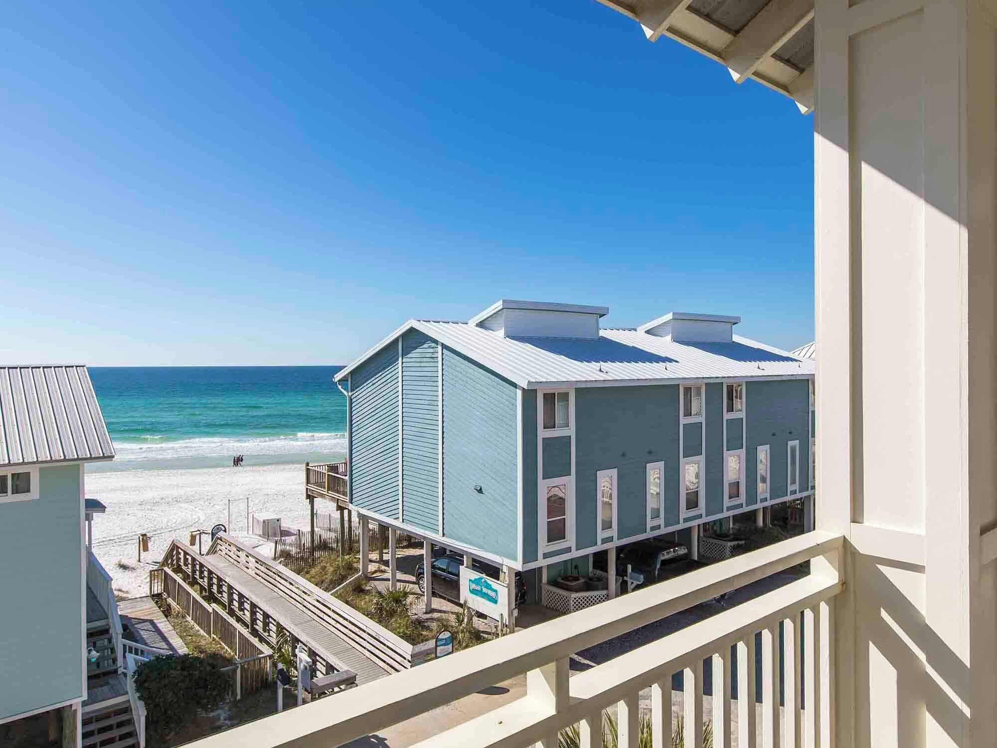 A beachfront hotel with a balcony overlooking the ocean, a covered walkway, and a beach area.