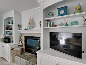 Cozy living room with a fireplace, flat-screen TV, and bookshelf.