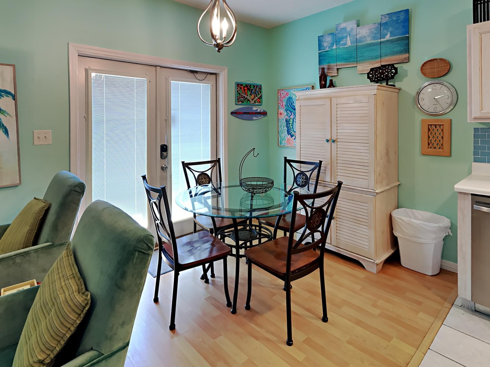 A dining area with a glass table and chairs, a white cabinet, and a door with blinds.