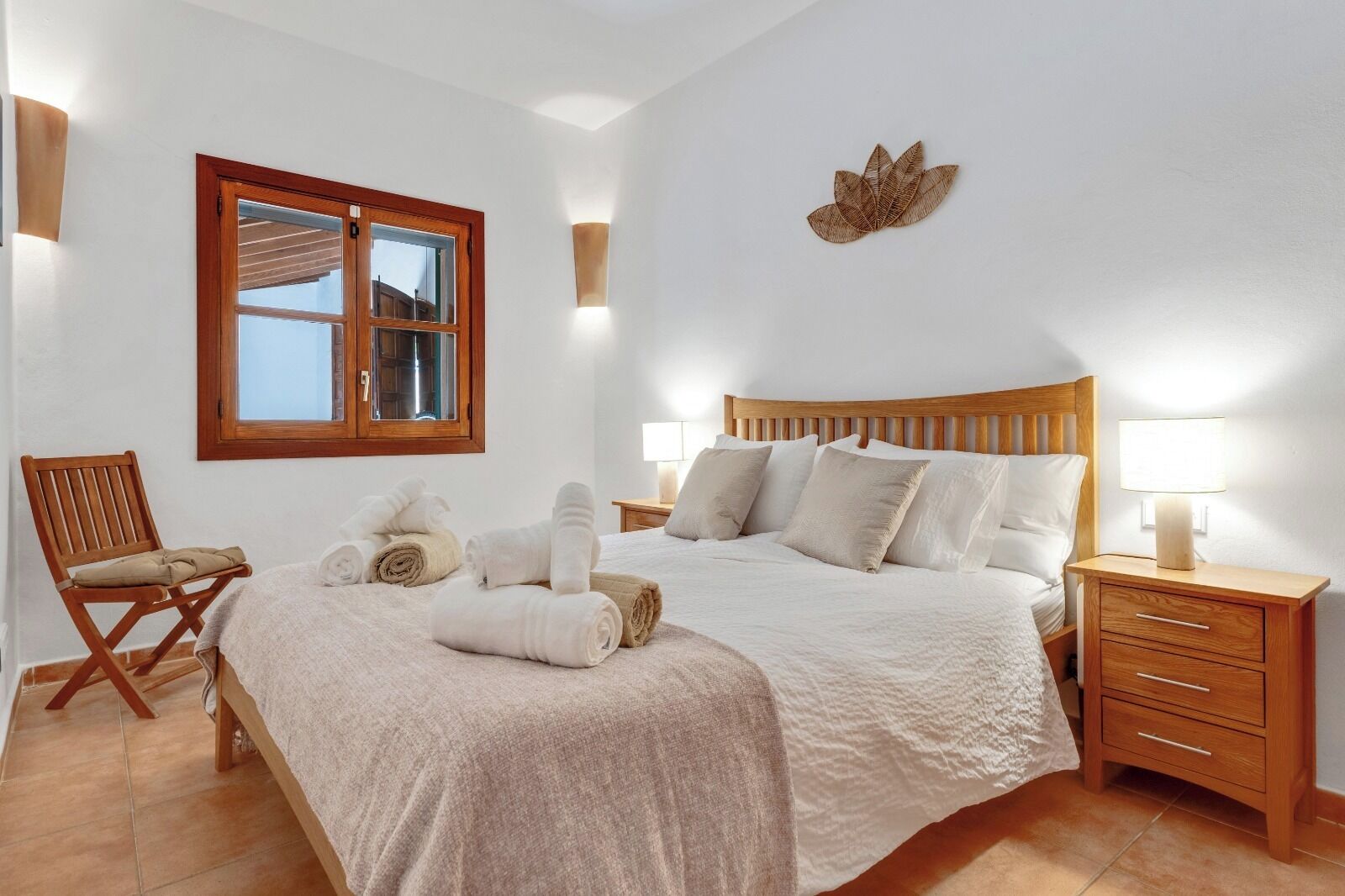 A bedroom with a bed, bedside tables, a chair, and a window.