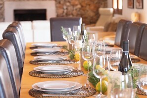 A dining table set with plates, glasses, and a bottle, surrounded by leather chairs.