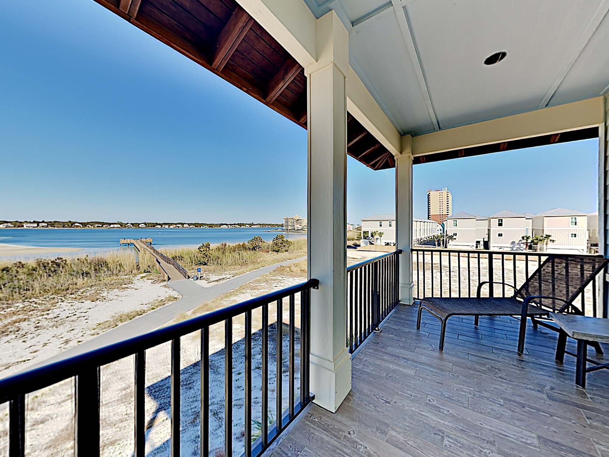 A covered balcony with a view of the beach and ocean.