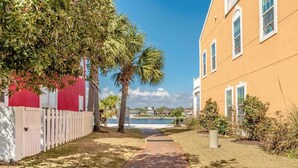 A pathway leading to a building with a red fence and palm trees.