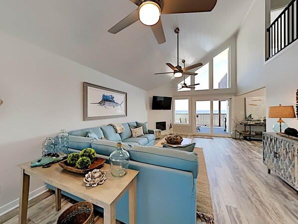 A spacious living area with a blue sofa, a wooden coffee table, and a ceiling fan. - So Shell Distancing by Southern Vacation Rentals (Gulf Shores)