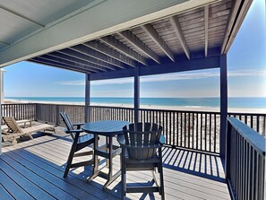 A covered deck with a table and chairs, overlooking a beach. - So Shell Distancing by Southern Vacation Rentals (Gulf Shores)