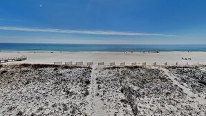 Ein Strand mit einer Holzpromenade, die zum Ufer führt, feinem Sand und dem Meer.
