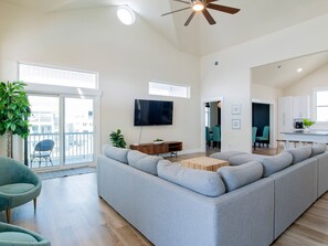 Relax in this spacious living room with a large sofa, flat-screen TV, and ceiling fan.