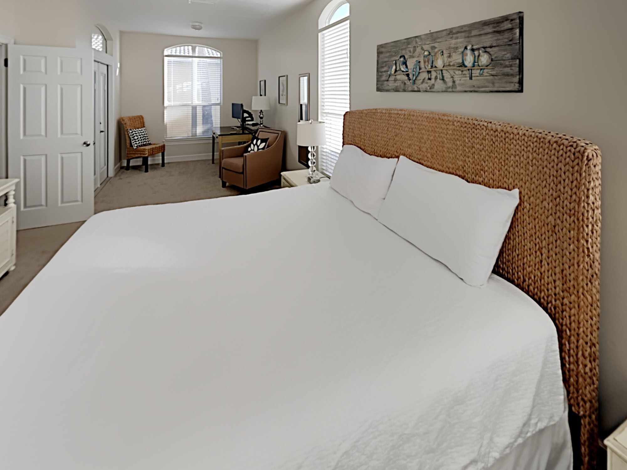 A bedroom with a large bed, a dresser, a chair, and a window with blinds.