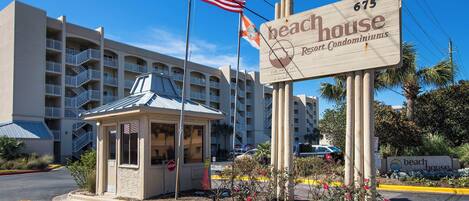 A beach house resort condominium with a sign indicating 675 units, a small kiosk, and an American flag.