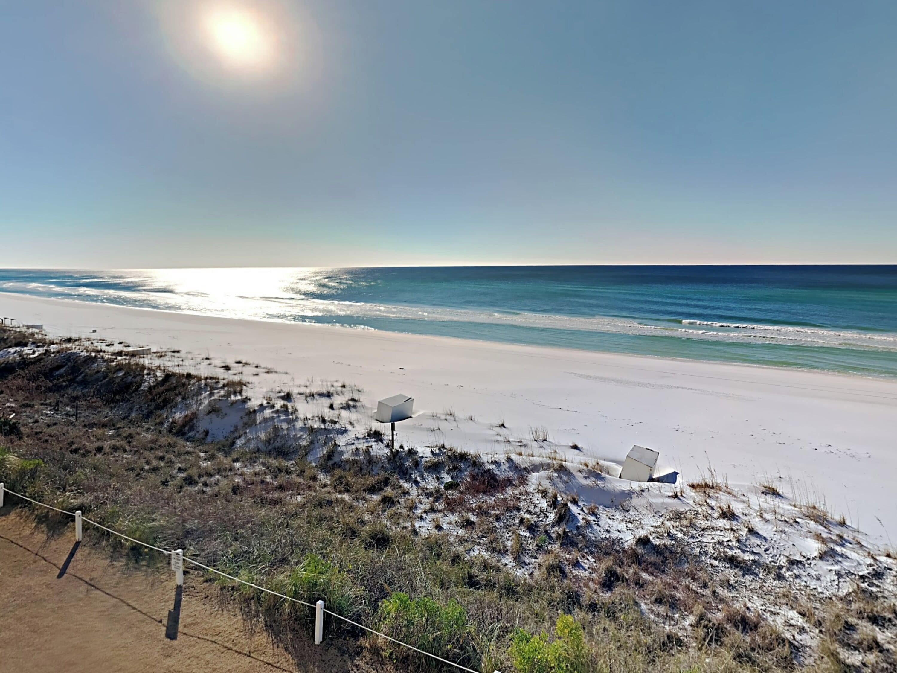 A beach with a sandy shore, a clear sky, and a body of water.