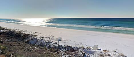 A beach with a sandy shore, a clear sky, and a body of water.