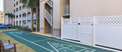 Un patio con una cancha de juego de hojalata, un banco y una cerca blanca.