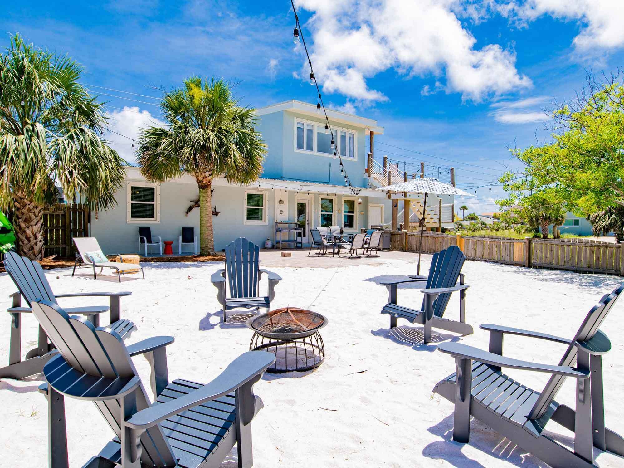 A beachfront property with a patio area featuring outdoor seating and a fire pit.